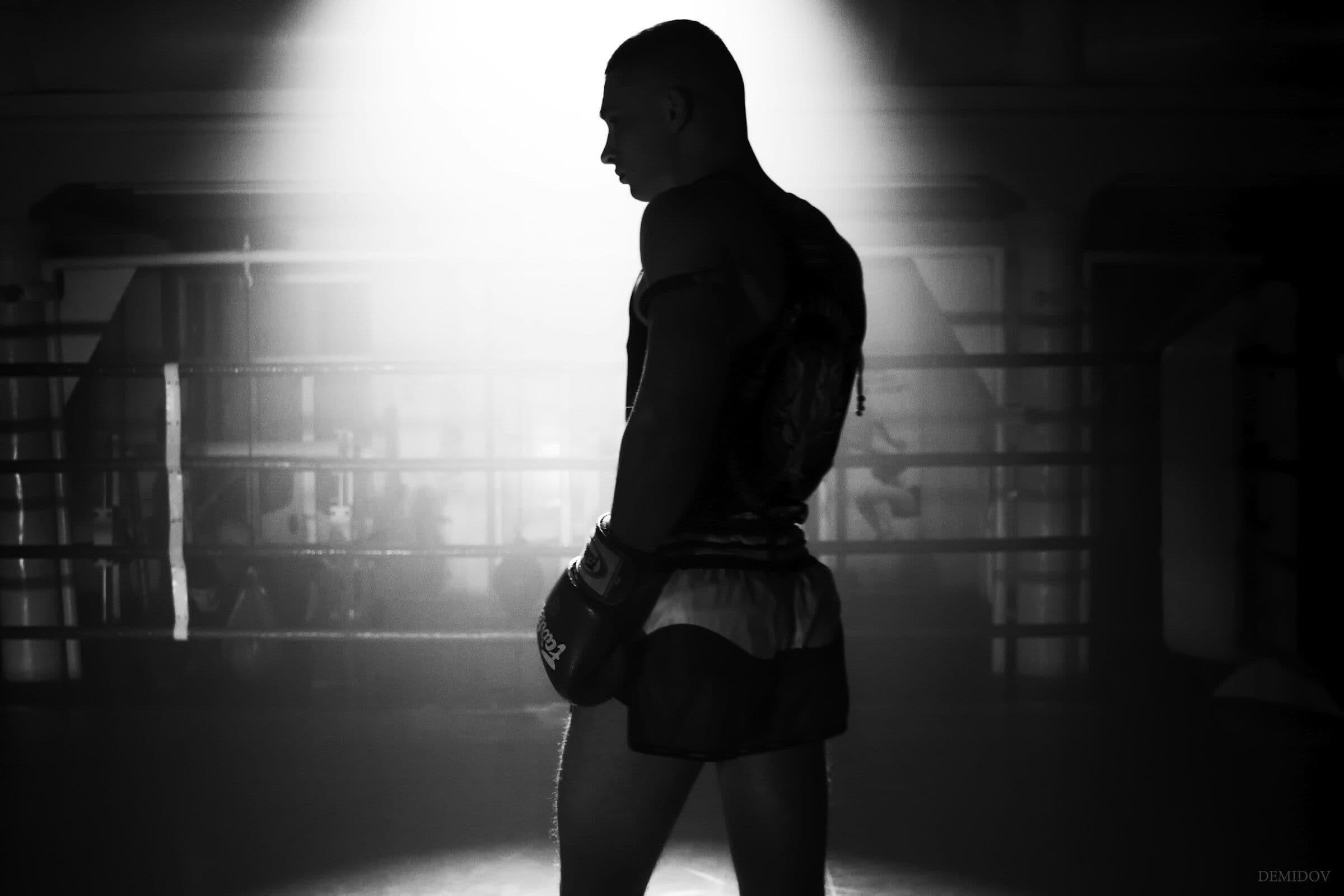 A boxer standing in a spotlight in an empty gym